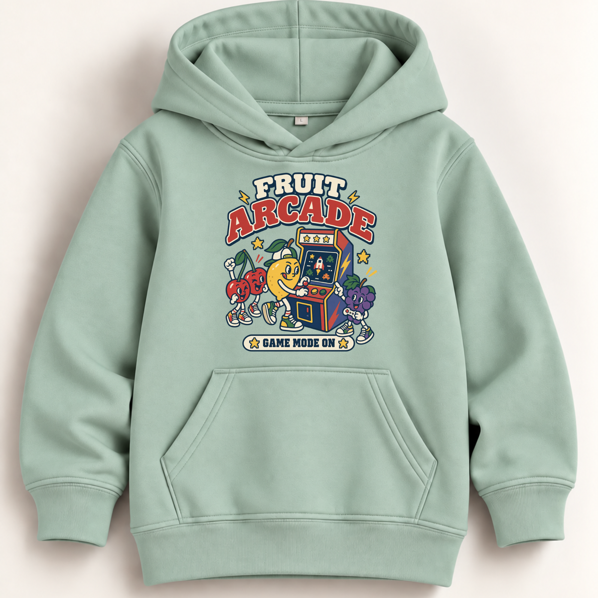 A sage green pullover hoodie with a colorful retro 'Fruit Arcade' graphic on the chest, featuring cartoon characters and arcade machines, shown against a light beige background.