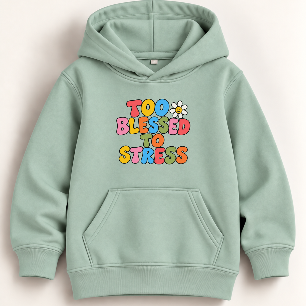 A sage green pullover hoodie with a colorful retro-style graphic on the chest reading 'TOO BLESSED TO STRESS' in multicolored bubble letters, accompanied by a small white daisy. The hoodie is shown flat against a light beige background.