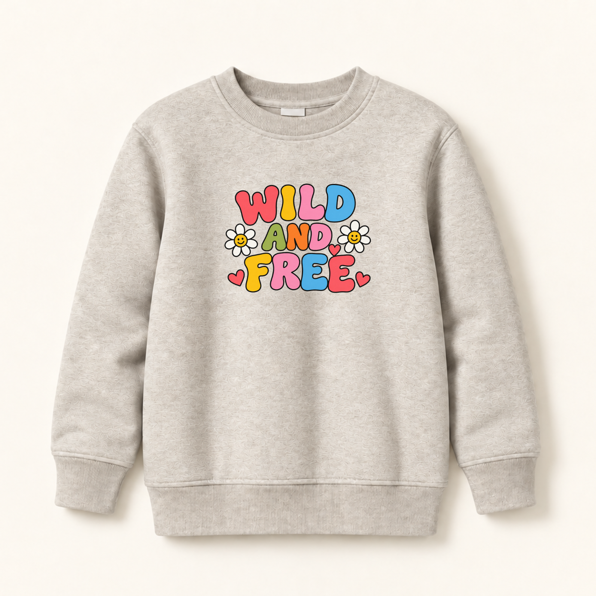 A light heather gray crewneck sweatshirt featuring a colorful retro graphic that reads 'WILD AND FREE' in bubble letters with daisy and heart accents, displayed on a clean off-white background.