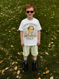 Child wearing a white t-shirt with Good energy only tee design on a grassy background
