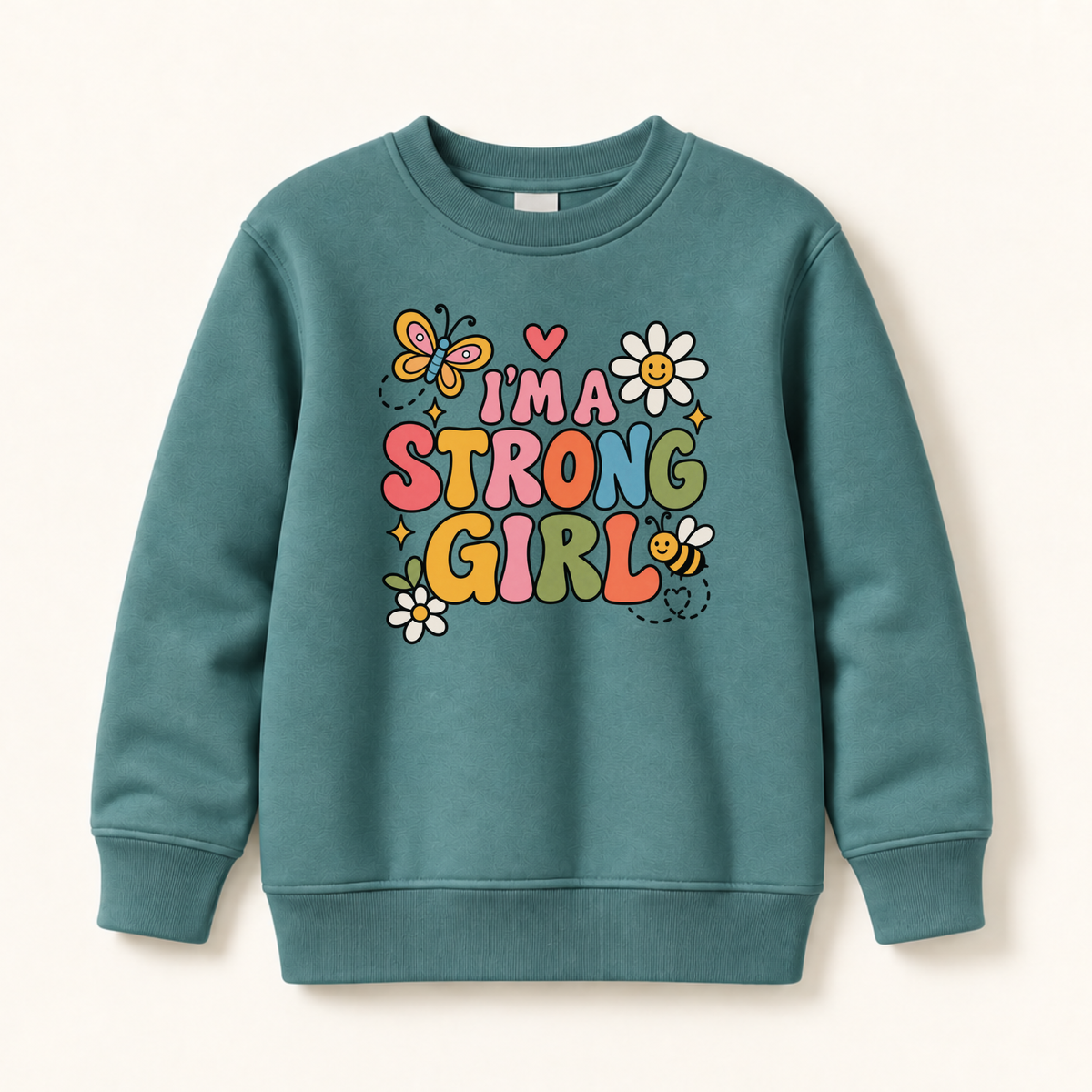 A teal crewneck sweatshirt with a colorful graphic on the front that reads 'I'M A STRONG GIRL' in playful multicolor letters, decorated with cartoon butterflies, flowers, and a bee, shown on a light beige background.