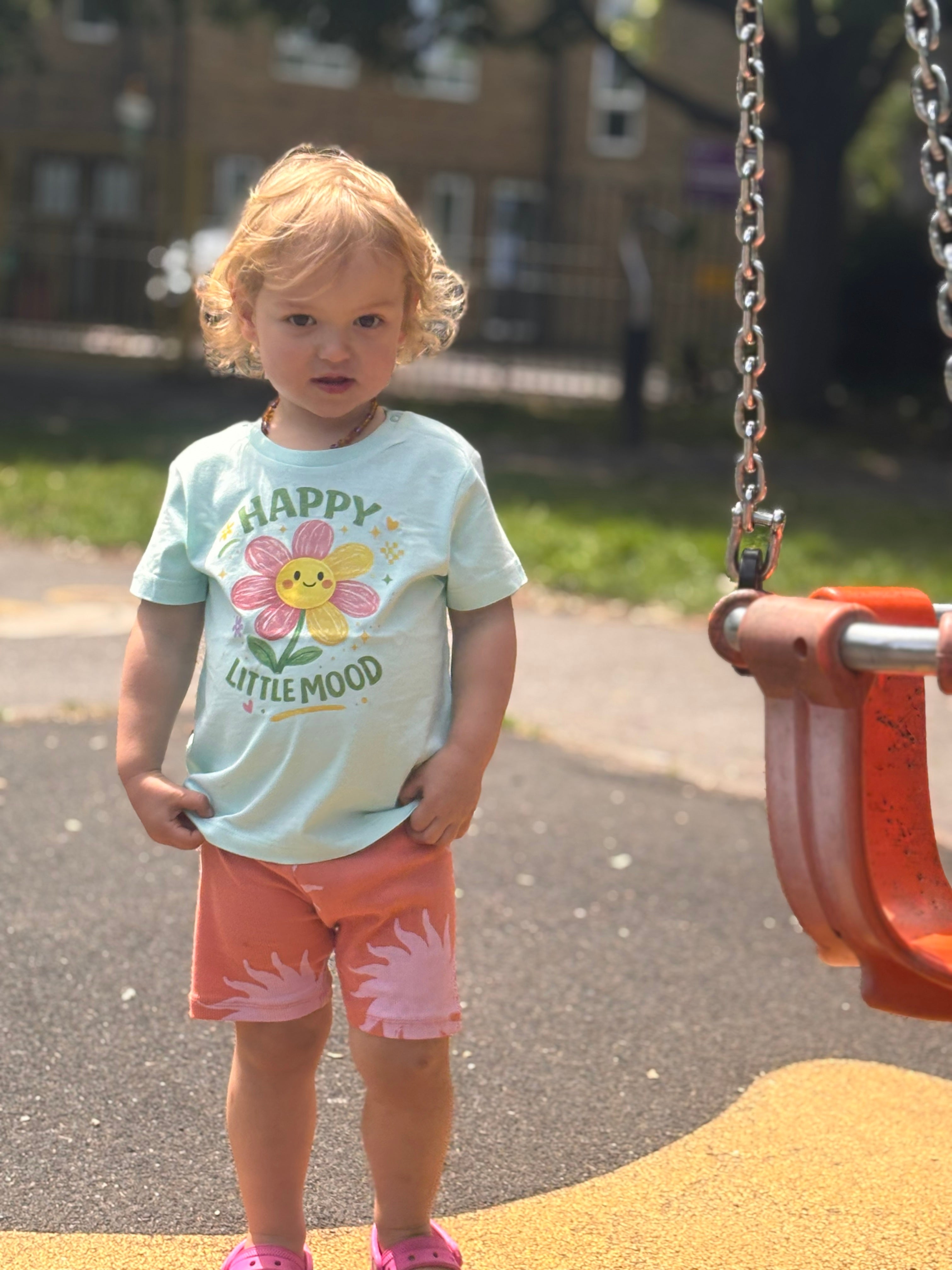 Child standing on a playground with a swing set in the background