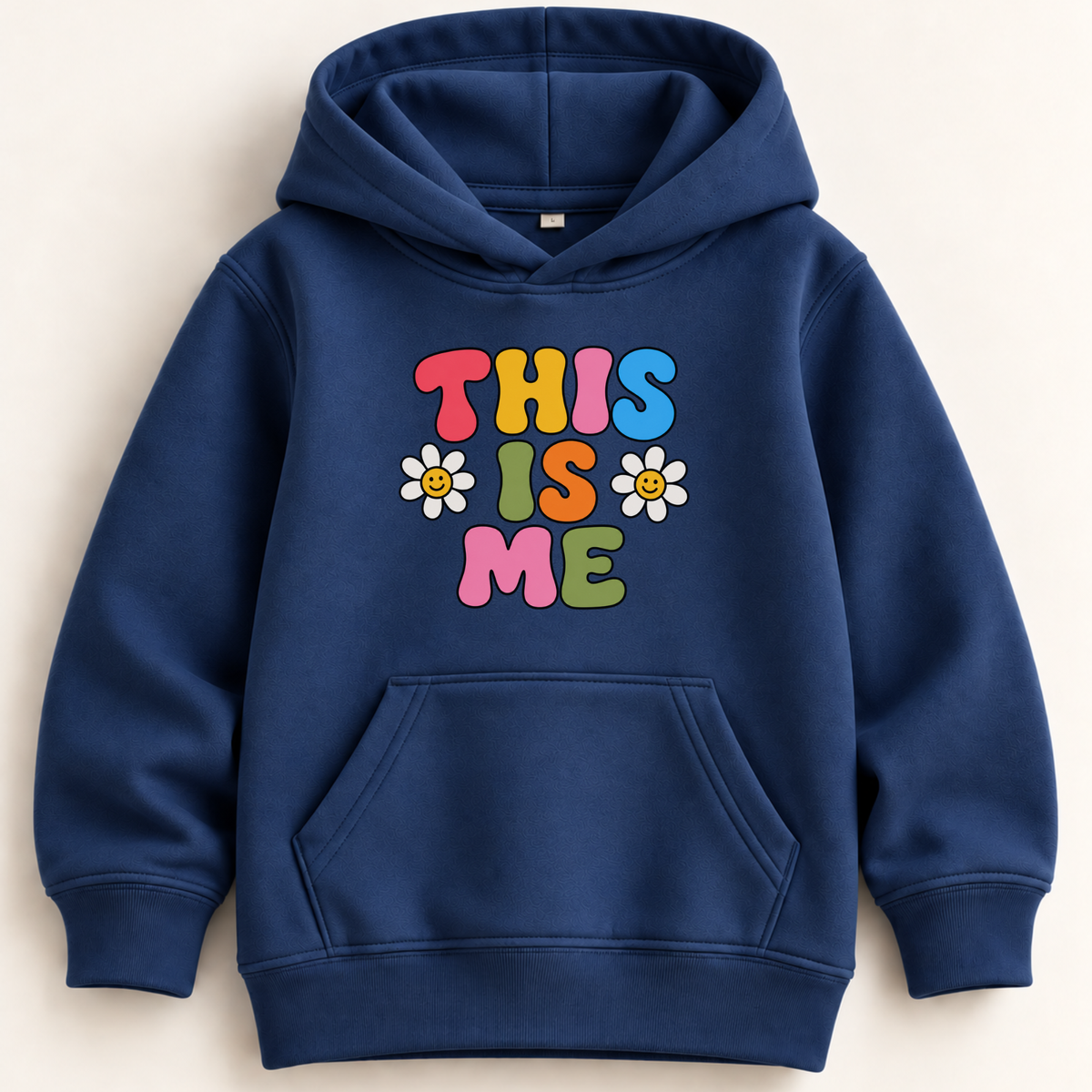 A navy blue pullover hoodie with a front kangaroo pocket and a colorful graphic on the chest that reads 'THIS IS ME' in bubble letters with daisy flowers, shown on a light beige background.