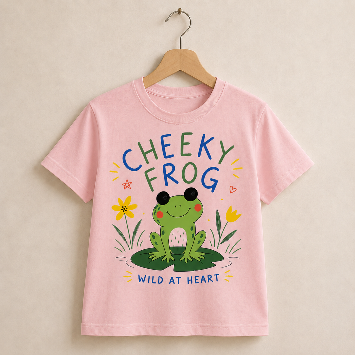 Pink t-shirt with a colorful 'Cheeky Frog' design on a beige background