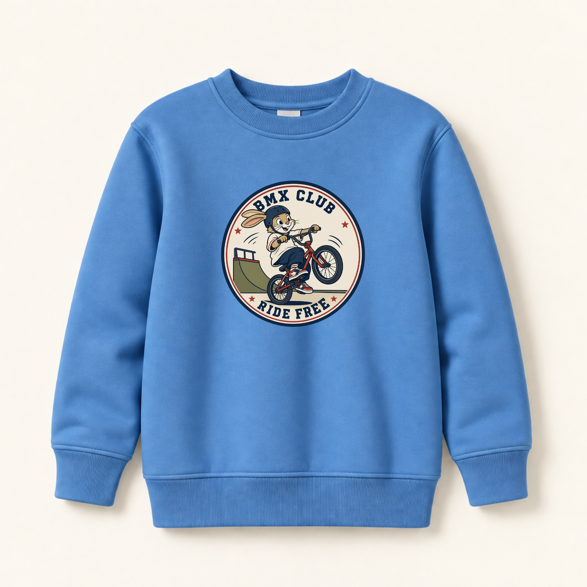 A blue crewneck sweatshirt featuring a circular graphic on the chest with a cartoon BMX rider and the text 'BMX CLUB RIDE FREE', displayed against a light cream background.