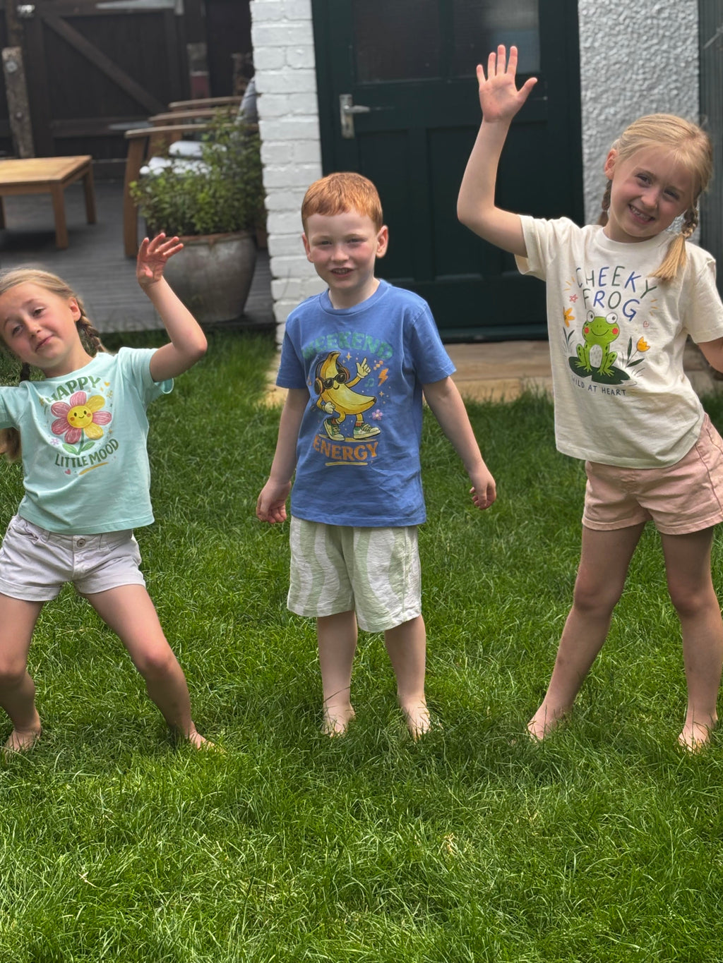Three children playing in a grassy area with a house in the background