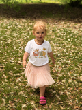 Child wearing a 'Wild' t-shirt in a grassy outdoor setting