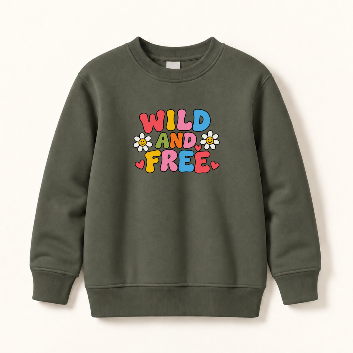 An olive green crewneck sweatshirt featuring a colorful retro-style graphic that reads 'WILD AND FREE' in bubble letters with small daisy and heart accents, displayed on a clean off-white background.