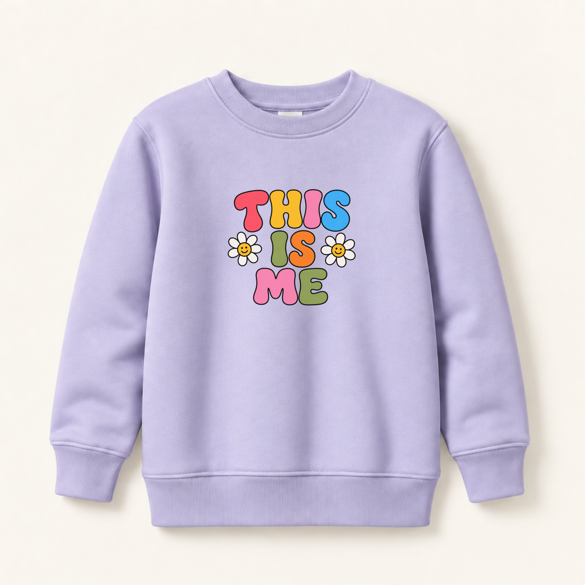 A light purple crewneck sweatshirt featuring a colorful retro-style graphic that reads 'THIS IS ME' in bubble letters with three small daisy flowers, displayed on a warm off-white background.